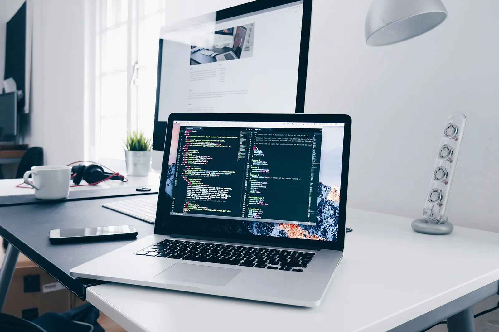 An office showing a laptop with website design coding development on the screen