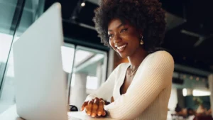 Smiling beautiful young woman sitting on a laptop inside a café