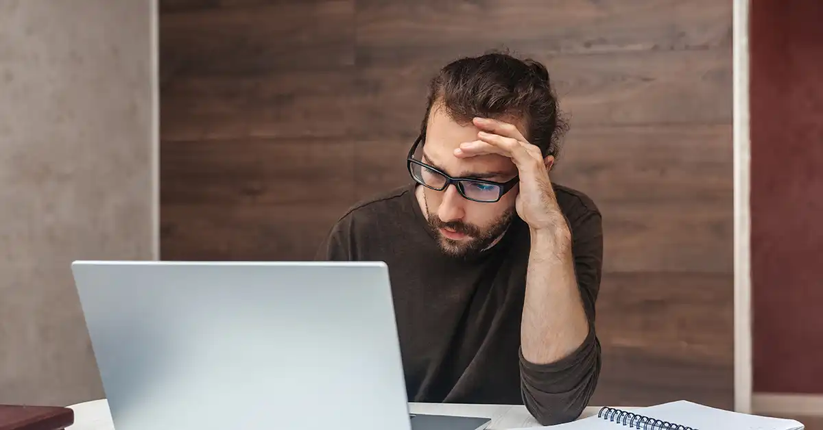 Frustrated man sat at a laptop